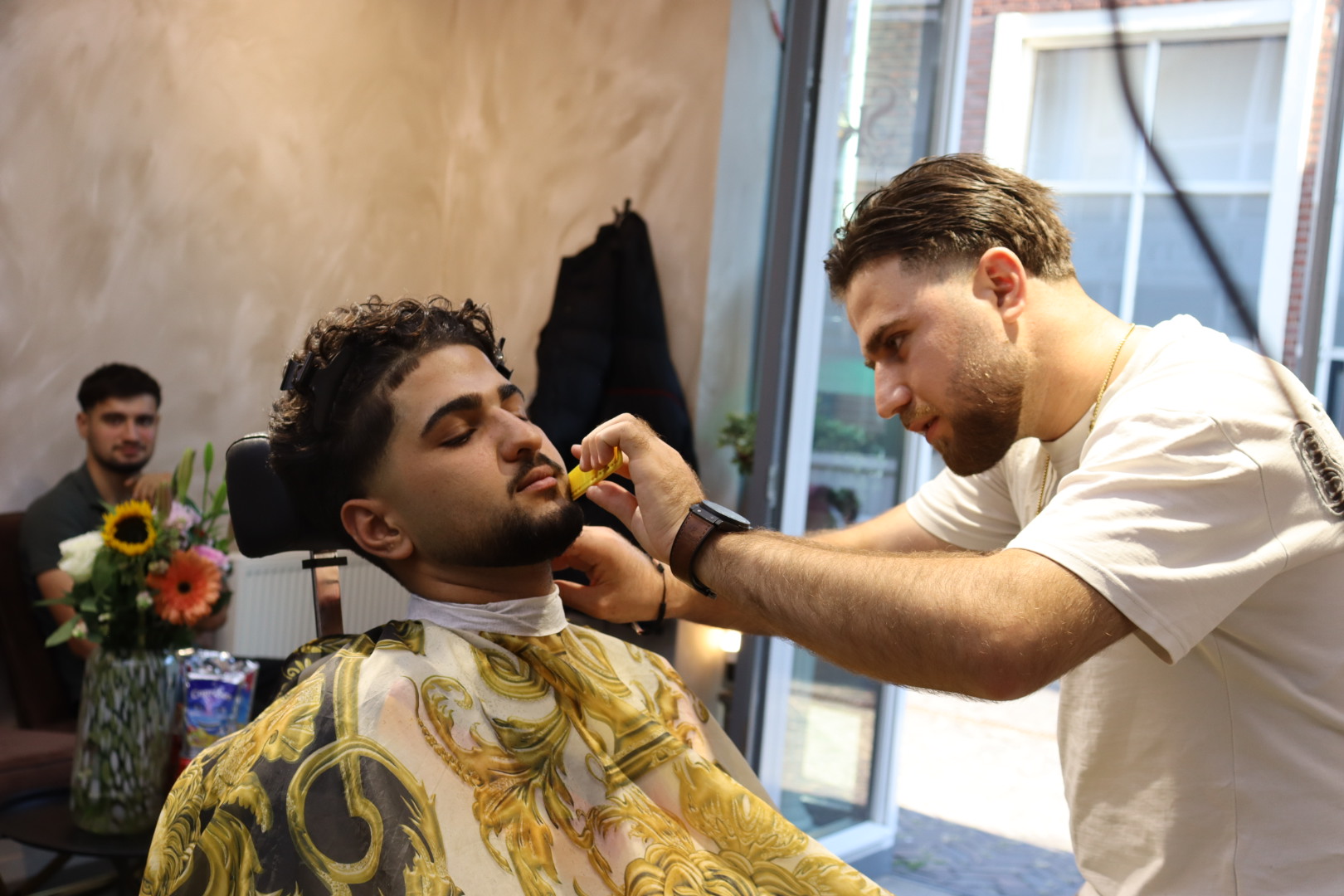 De kapper trimt de baard van een klant in de stoel