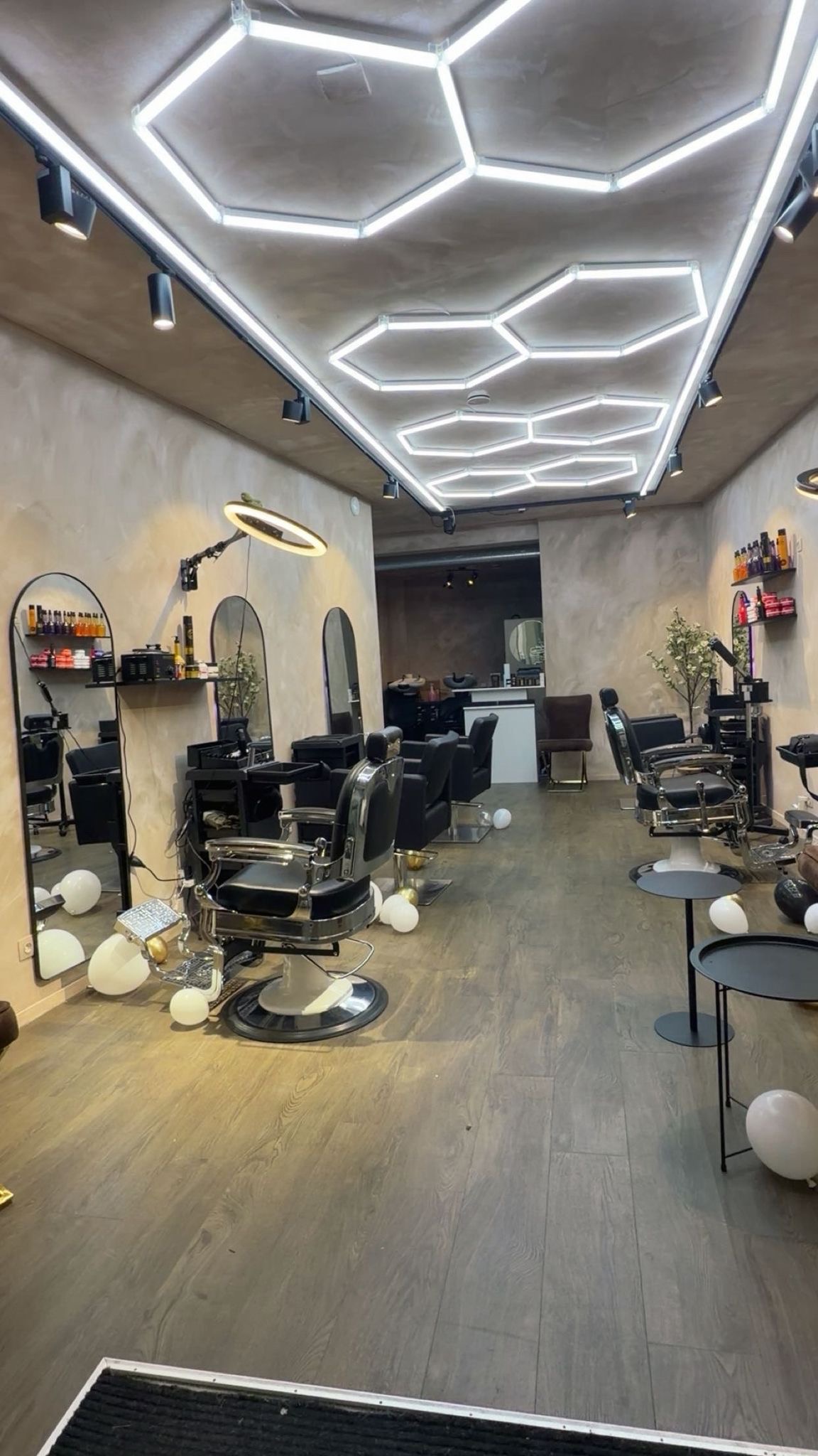 Lange blik door de salon, met het zeshoekige lichtplafond en de kappersstoelen